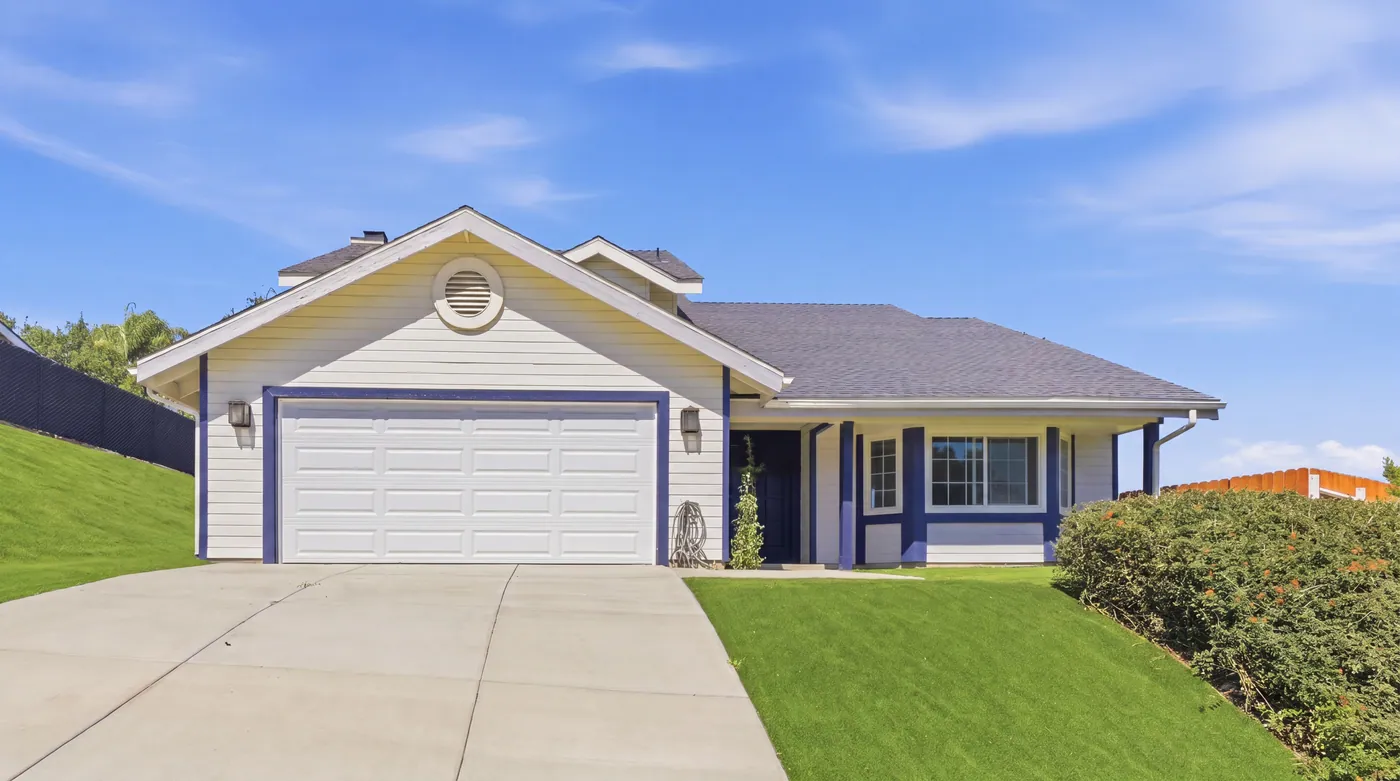 Daytime exterior view of a single-story home with driveway, lawn, and front landscaping