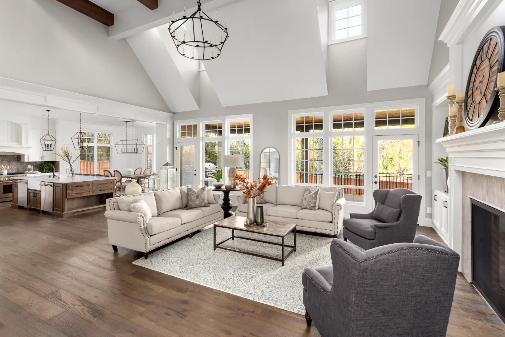 Bright open living room with large windows, fireplace, and adjoining kitchen