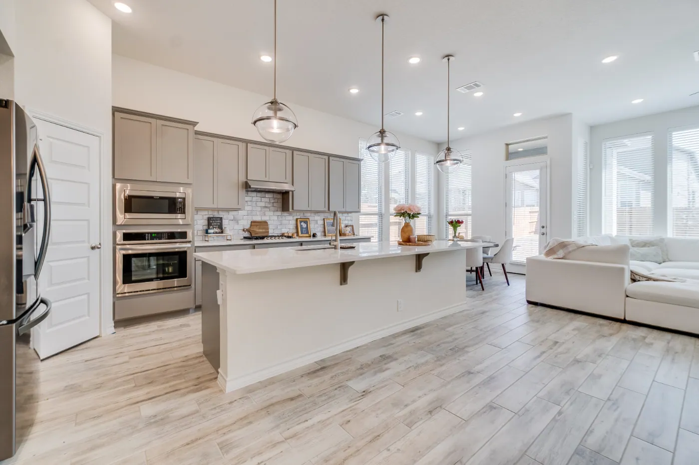 Open kitchen and living area with island, pendant lighting, and large windows